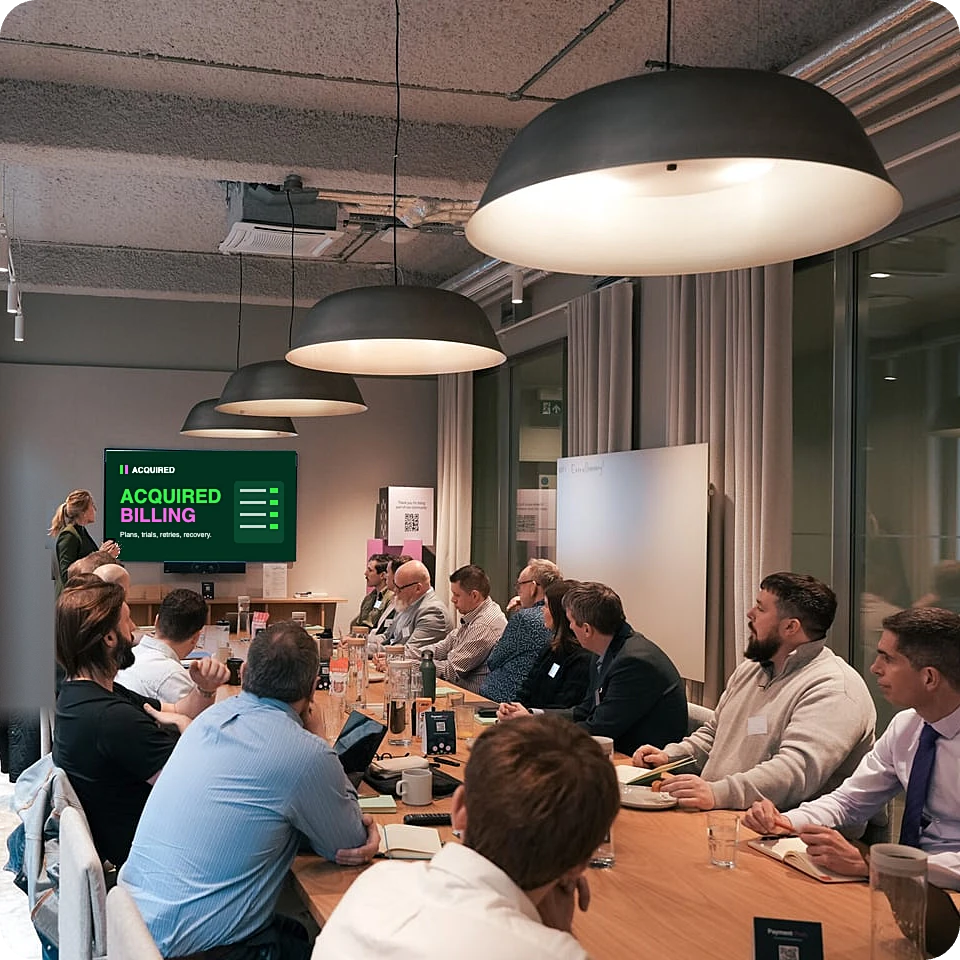 An Acquired team member presenting Acquired Billing to guests seated around a meeting table